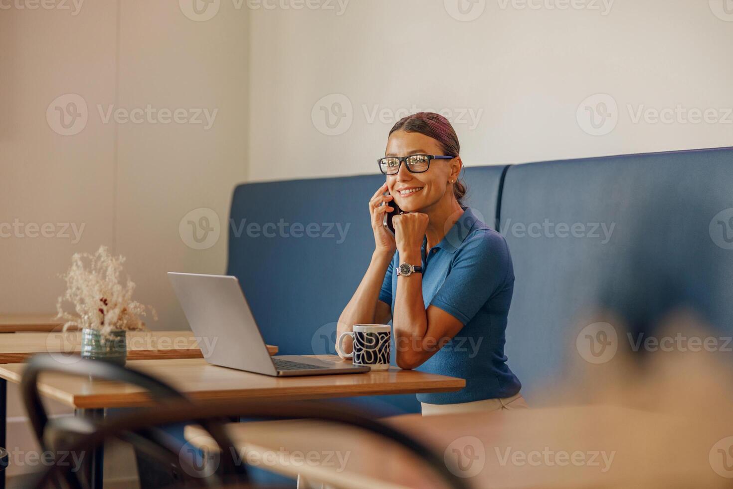 A woman is seen working remotely on her laptop while enjoying a cup of coffee beside her photo