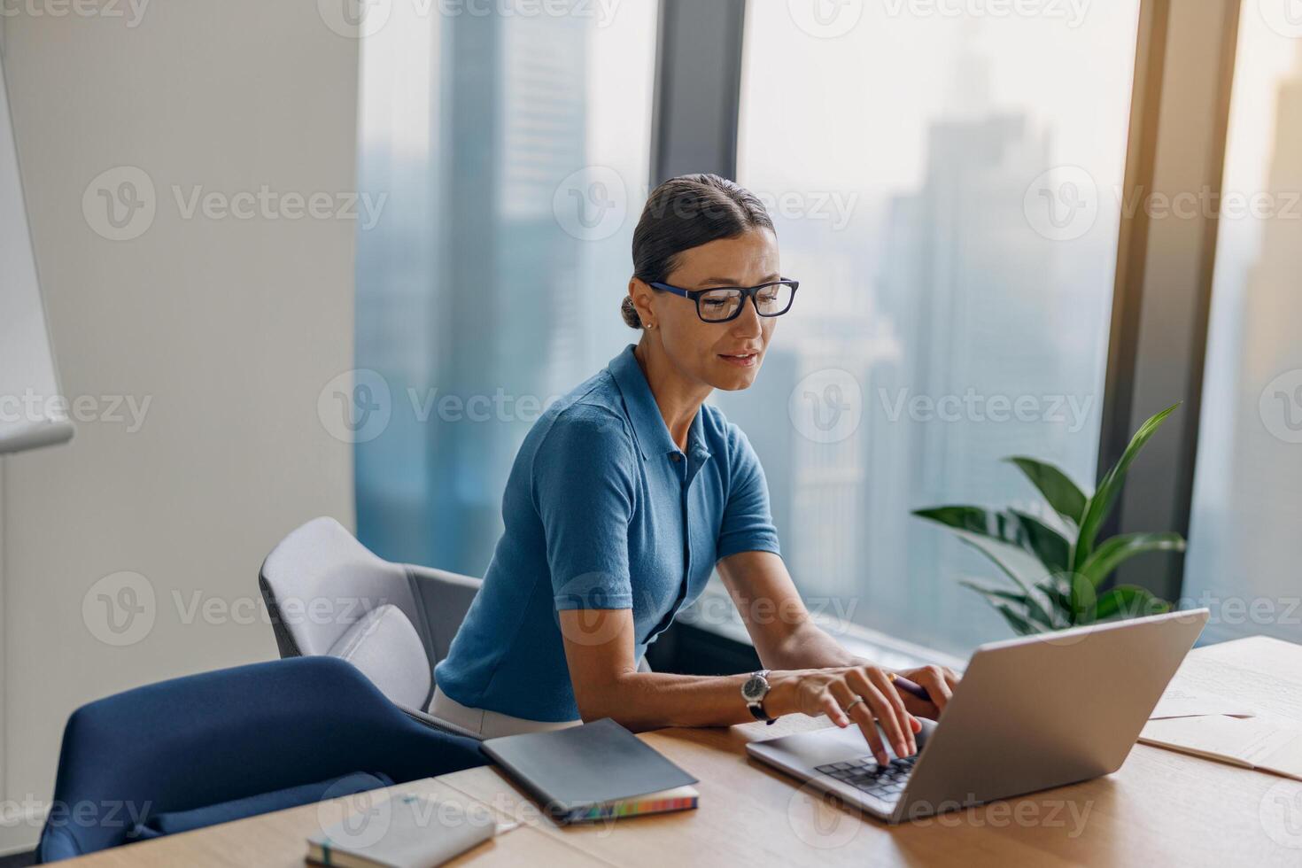 A Professional Woman Engaged in Her Work While Using a Laptop in a Modern Office Space photo