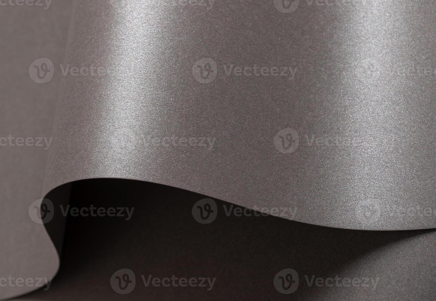 Gray glossy paper texture with a sleek, pearlescent finish, featuring wavy folds and edges. Elegant, photo