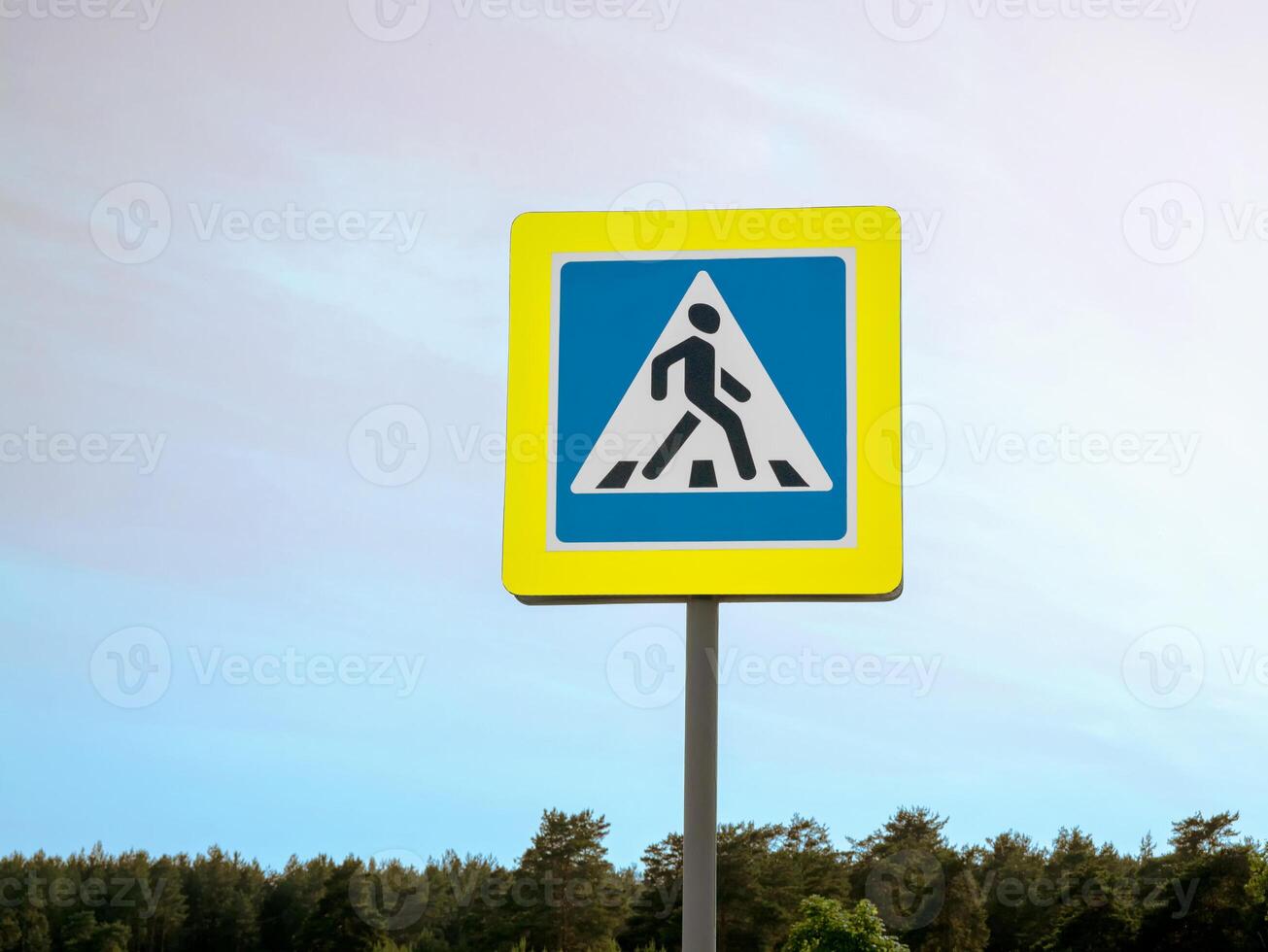 A road sign in the pedestrian crossing area against the sky. A warning about a pedestrian crossing. A reminder to follow the rules of the road. Pedestrian safety. photo