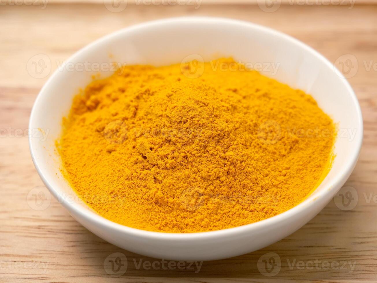 Aromatic spice in turmeric powder in a white cup on a wooden background. photo