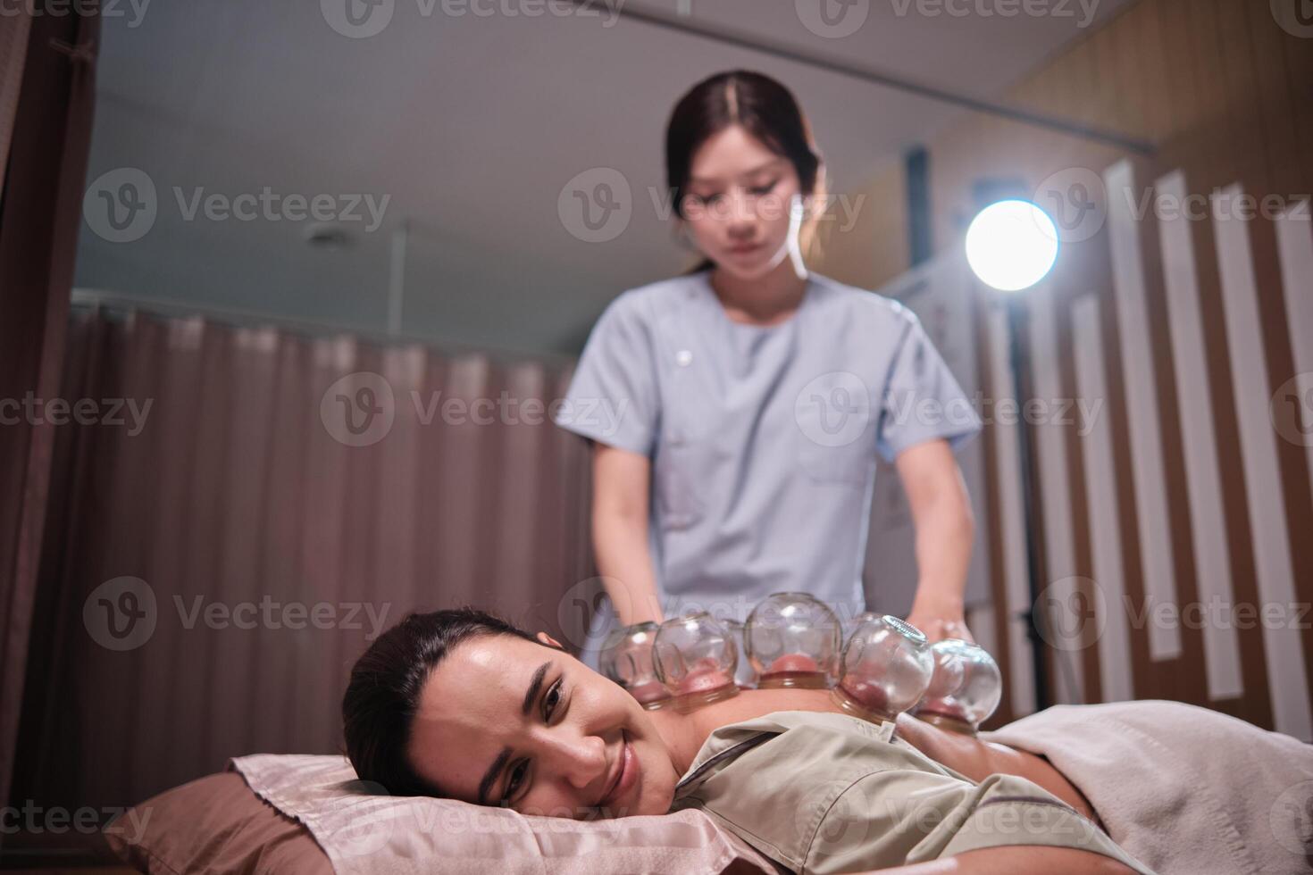 Beauty Latino woman is treated for health recovery with cupping therapy by Asian female physical doctor, an oriental traditional medicine therapist at a spa clinic, and wellness messaging lifestyle. photo