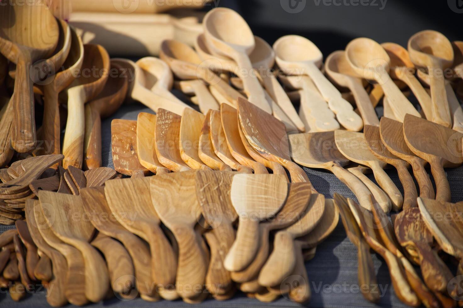 Beautiful display of artisanal wooden cooking spoons and spatulas shows natural wood grain texture. photo