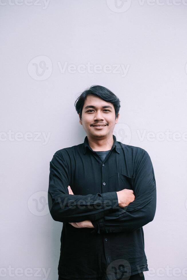 Confident smiling asian man portrait with arms crossed on neutral background photo