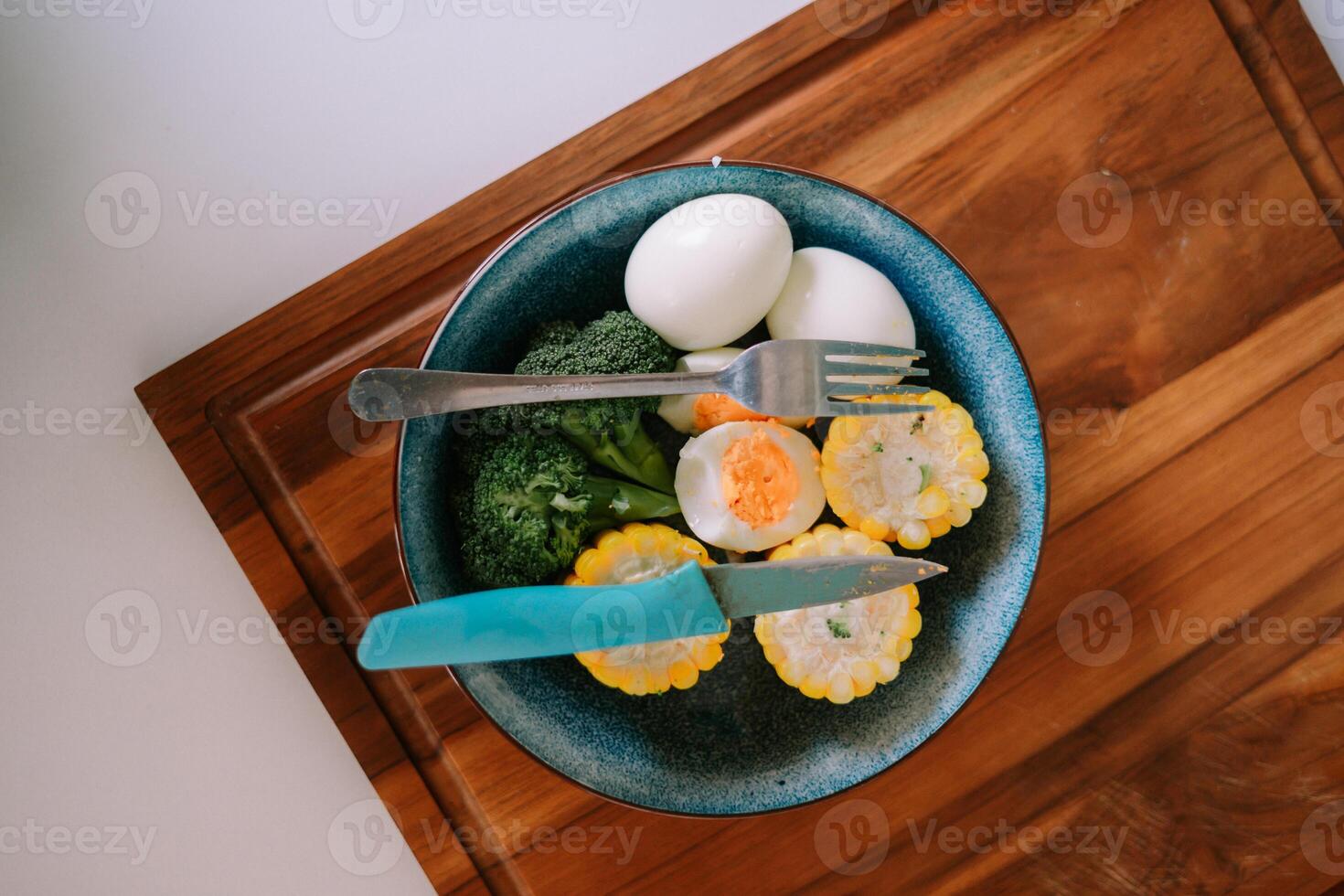 Nutritious plate with eggs, broccoli, and corn on a wooden board photo