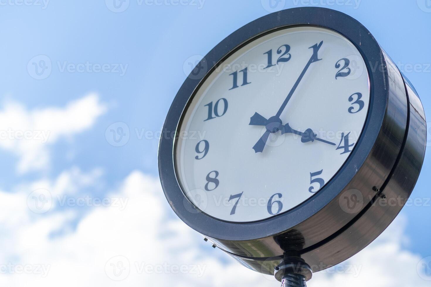 Vintage Clock on a Post Against a Blue Sky With Fluffy Clouds During Midday photo
