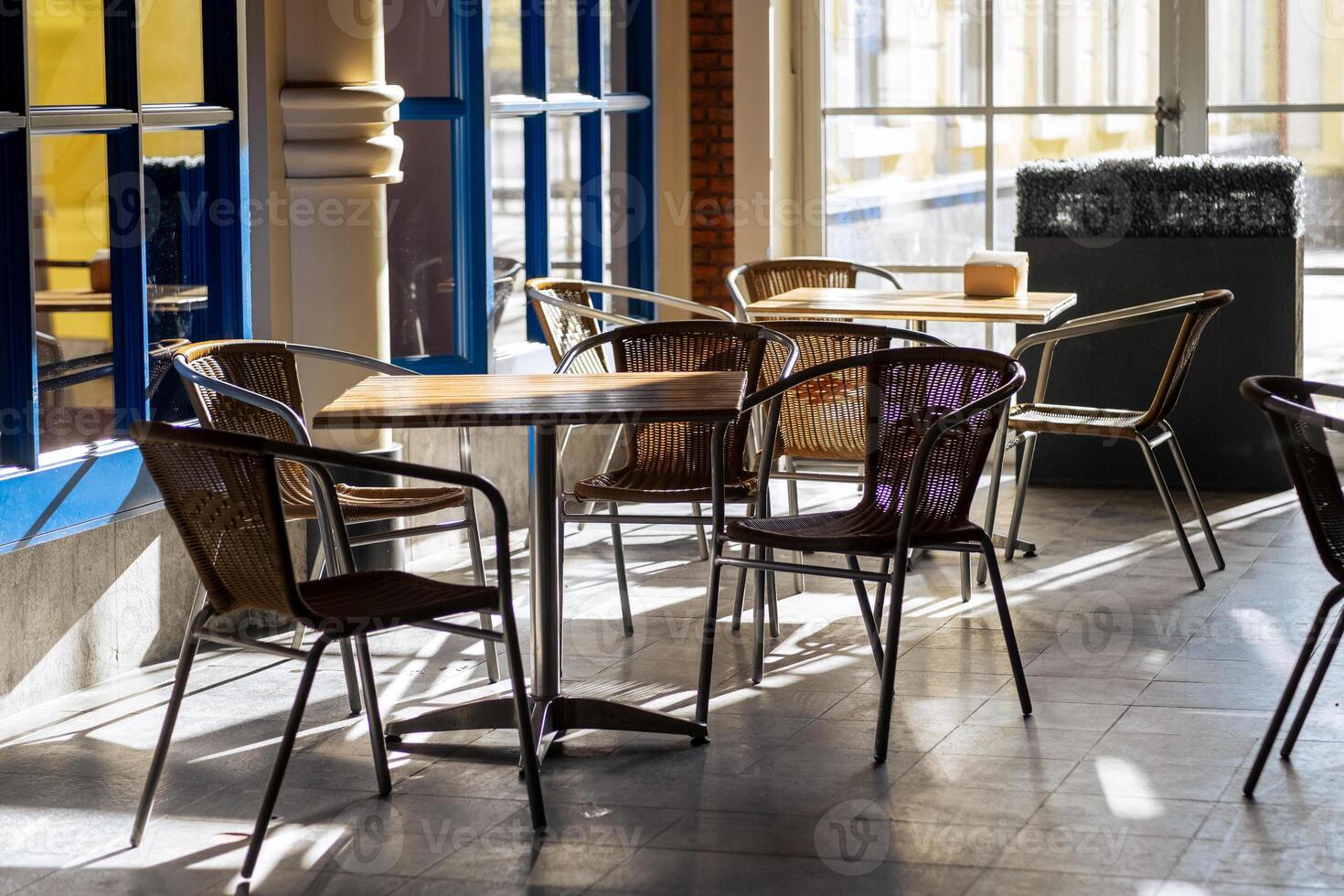 Cozy Cafe Interior With Wooden Tables and Wicker Chairs in Bright Natural Light During the Afternoon photo