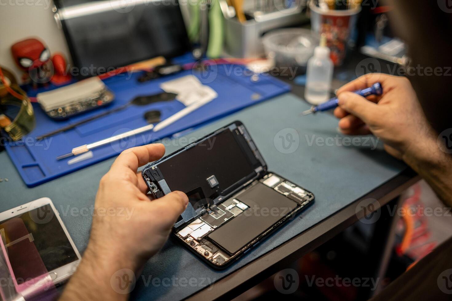 Technician Repairing Smartphone Screen in Workshop While Using Tools and Components to Ensure Device Functionality photo