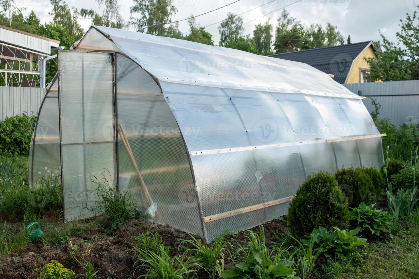 Greenhouse Made of Transparent Panels in a Garden Setting on a Sunny Day Offers Ideal Conditions for Plant Growth and Cultivation photo