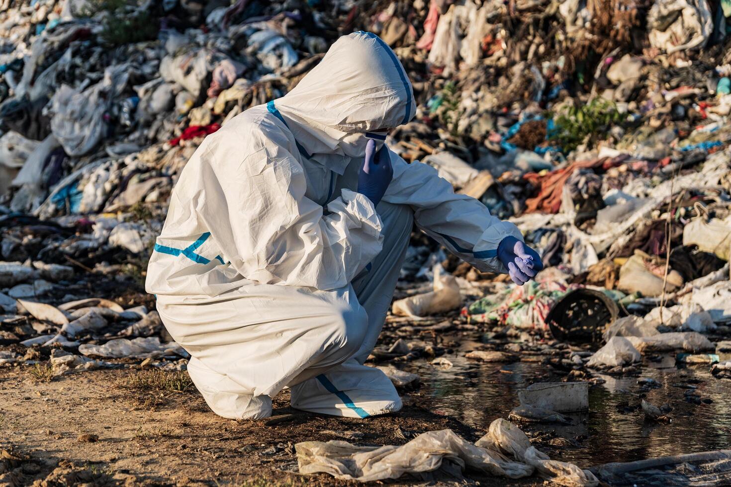 Sanitation worker at the landfill. Landfill with household waste. Environment pollution photo