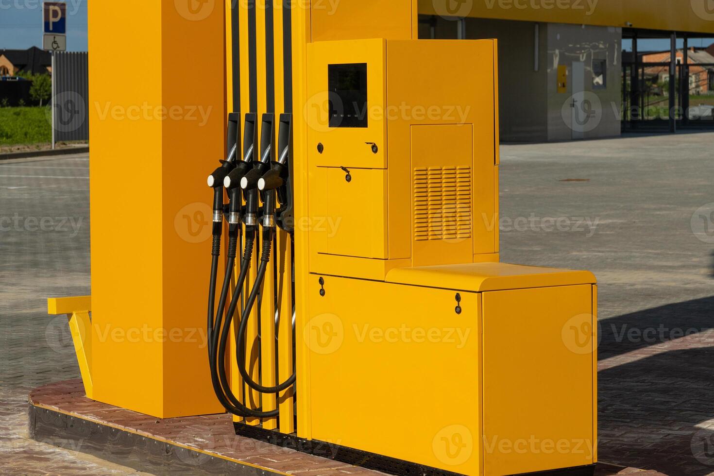 The bright yellow dispenser, featuring multiple hoses, is positioned at a gas station during the day, ready for vehicles to refuel conveniently photo