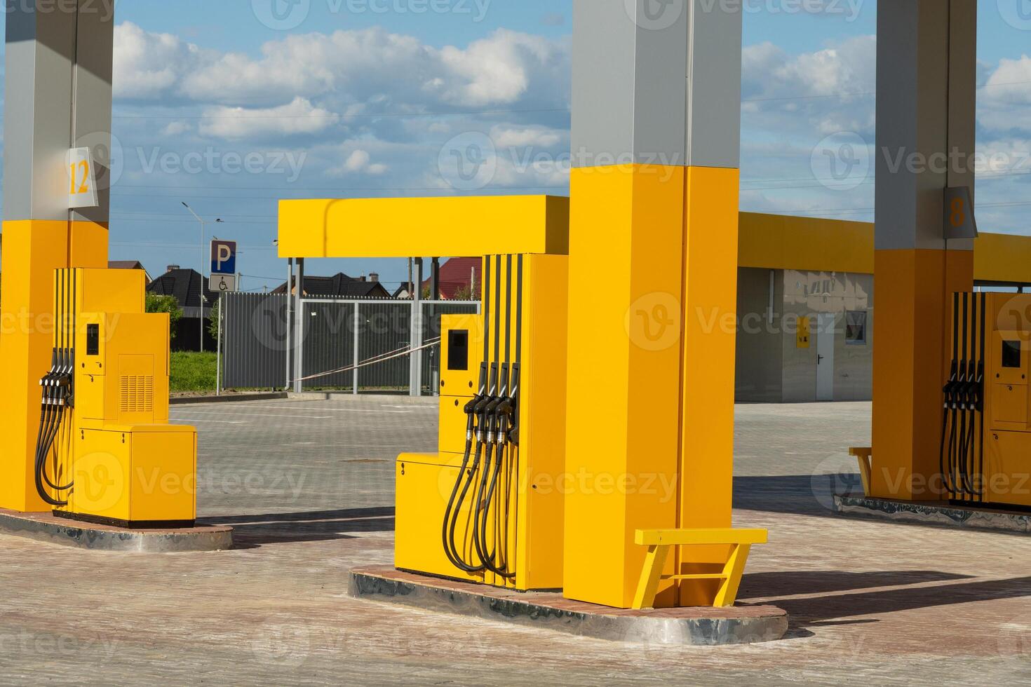 Bright yellow fuel pumps stand at a newly opened gas station with a blue sky overhead. The area is spacious and well-lit, offering a clean and modern look photo