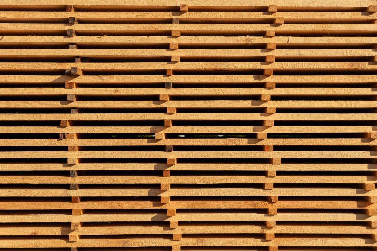 Vertical wooden slats are meticulously arranged to form a textured wall, showcasing natural wood grain in a brightly lit environment, creating a warm atmosphere photo