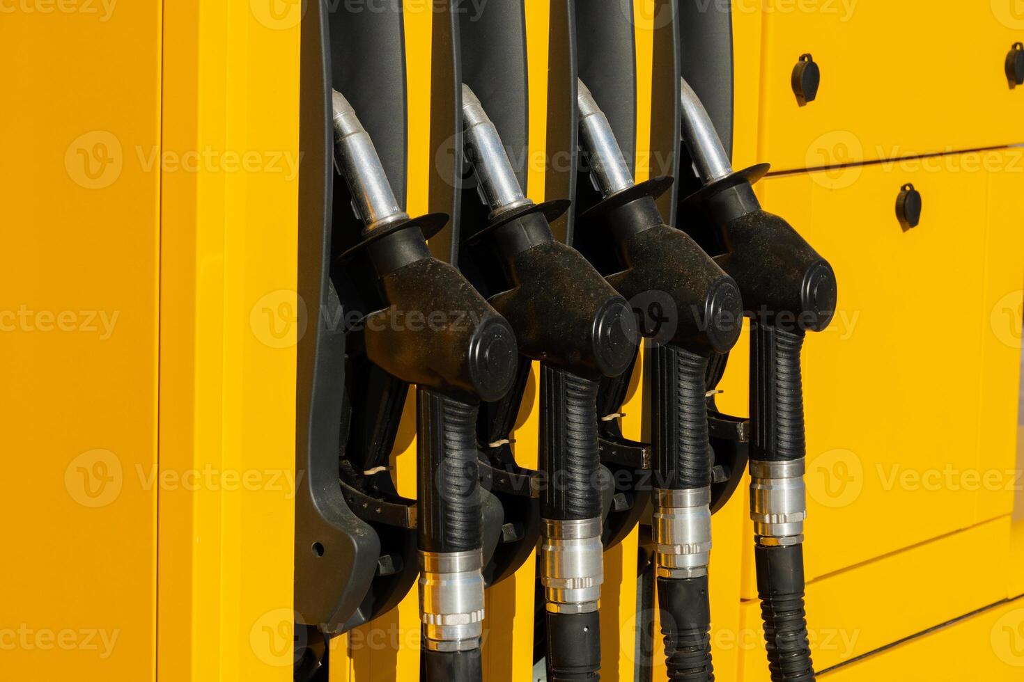 Multiple fuel dispensers stand ready at a vibrant yellow gas station, reflecting bright sunlight on a clear day. The scene highlights an accessible refueling experience photo