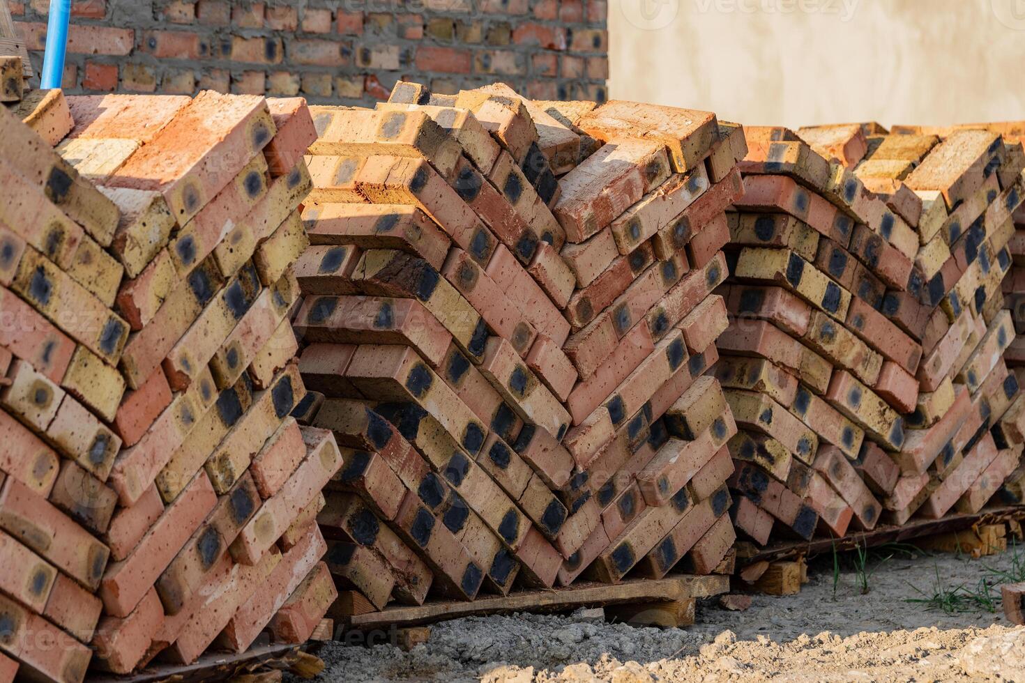 A large pile of stacked bricks arranged neatly at a construction site under bright daylight, showcasing the materials for upcoming building efforts in an urban environment photo