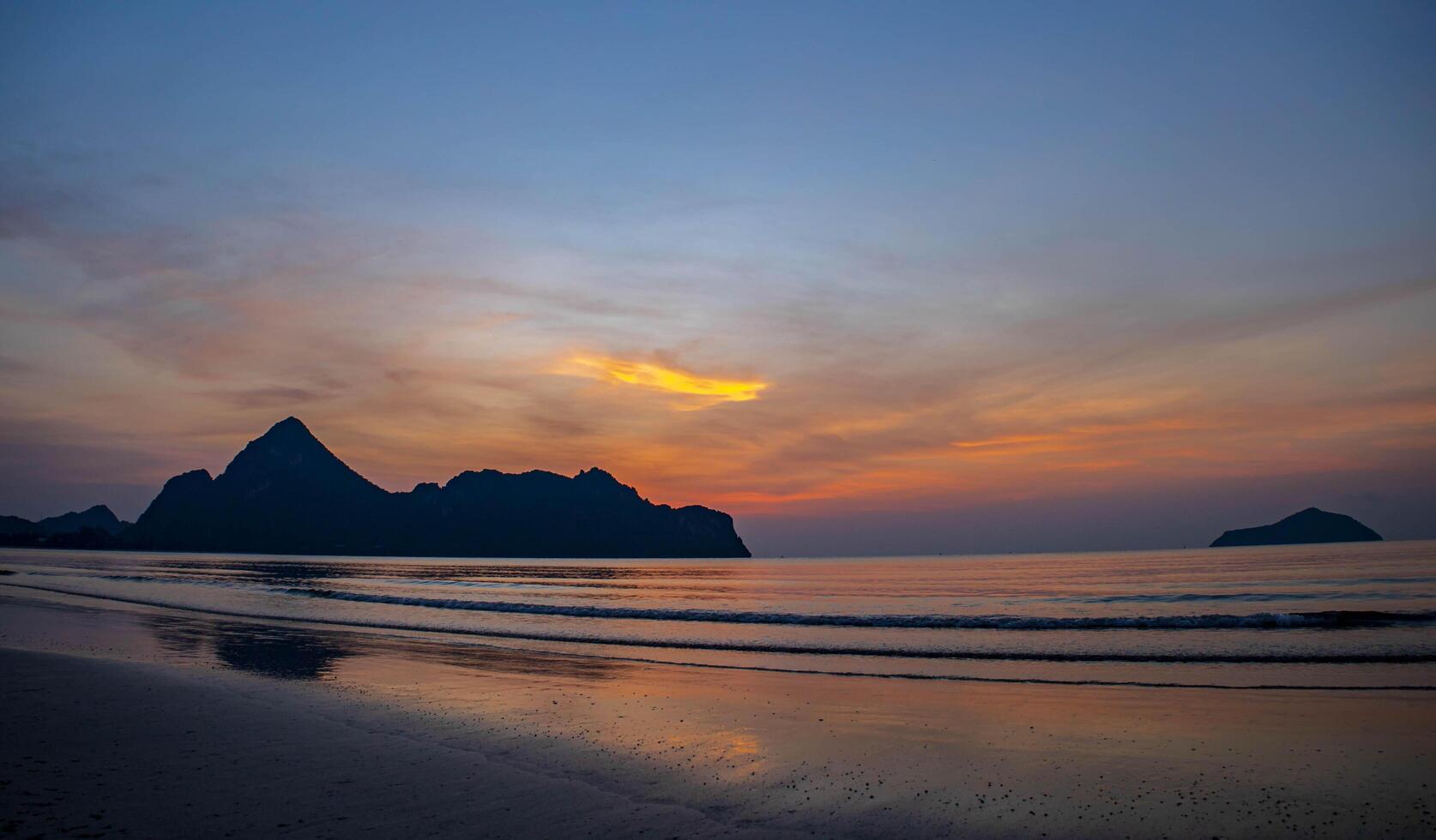 Golden light streams across the sea like threads of silk, and the beach, untouched and quiet, waits to welcome the new day. photo
