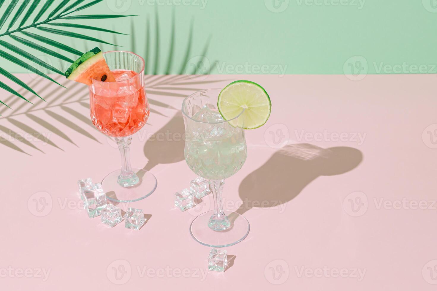 Summer scene with watermelon and lime drinks and palm leaves shadow on pink and green background. Sun and shadows. Minimal cocktail concept. Trendy summertime party idea. Summer aesthetic. photo