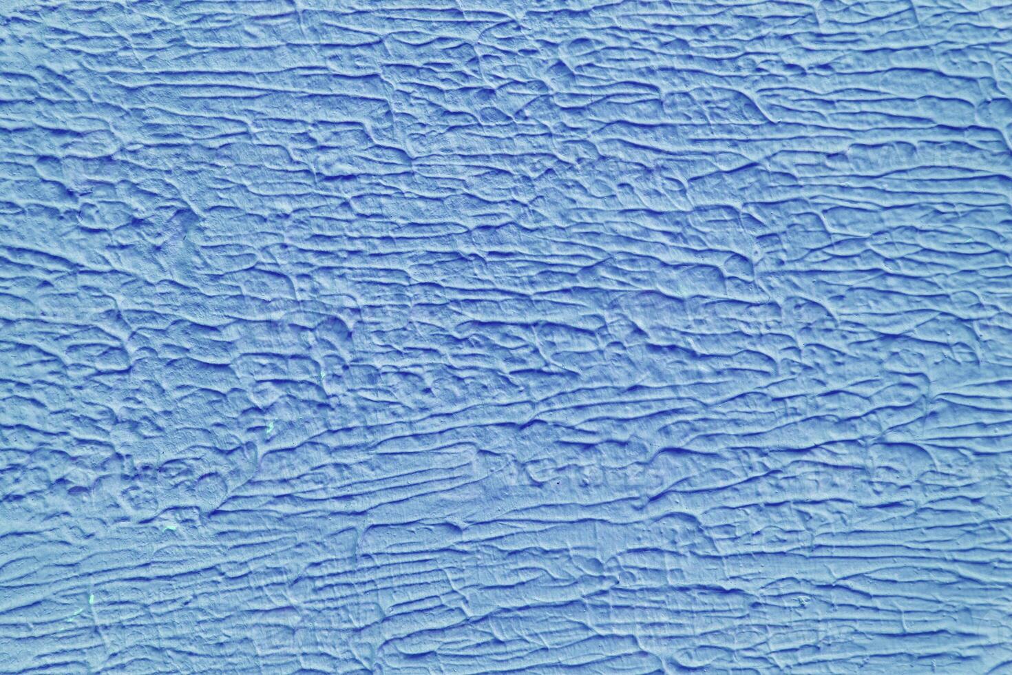 A wall with a blue paint that has a texture. The texture is made up of lines and swirls. photo