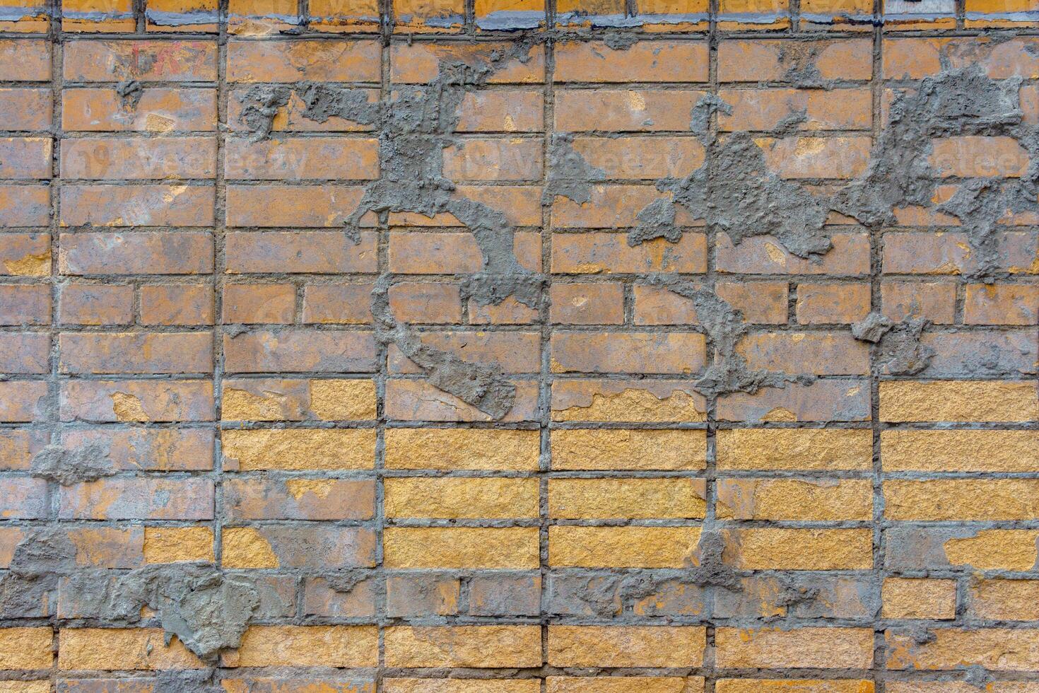 A yellow brick wall is marked with irregular splashes of cement. The rough contrast adds an unfinished, industrial character. photo