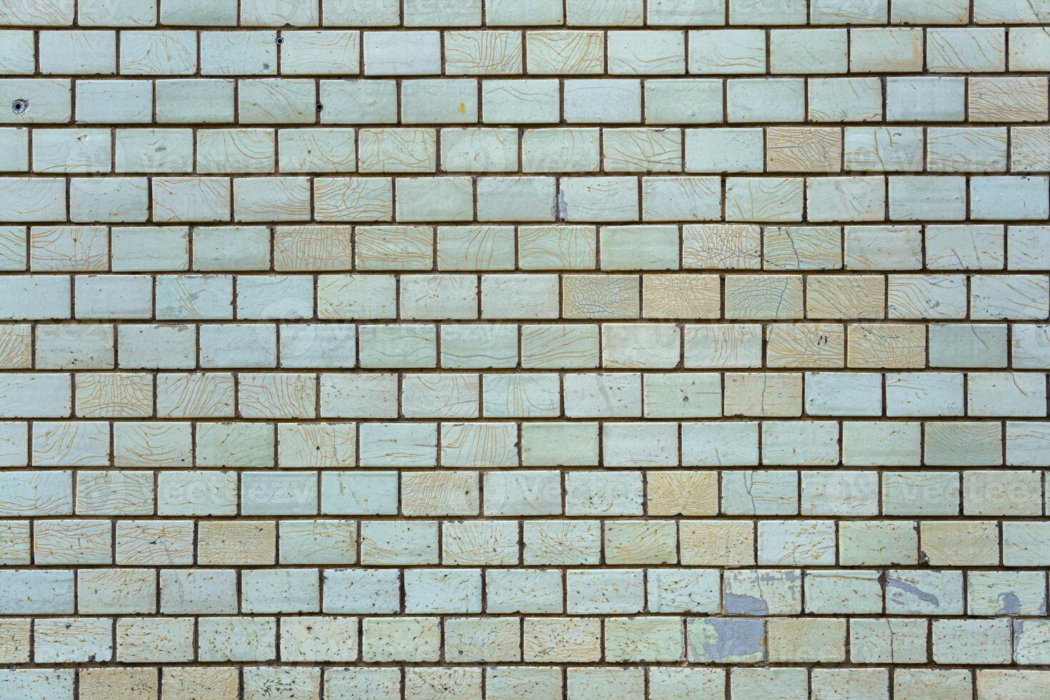Wall of vintage bricks covered with cracked glaze. Bricks are arranged in a pattern. photo
