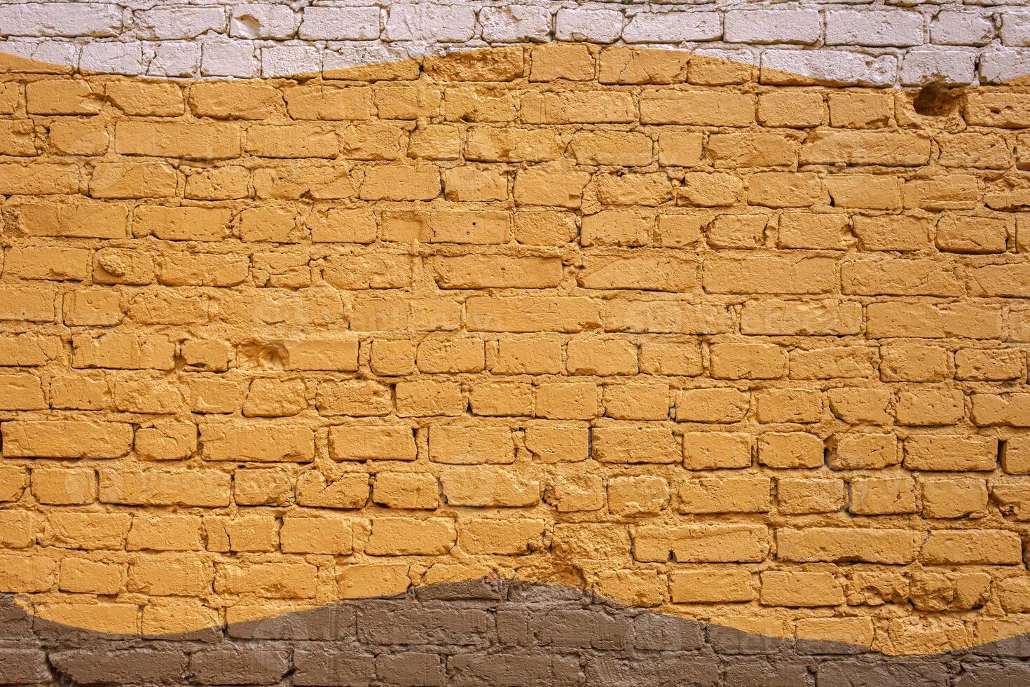 A white brick wall is adorned with a wide yellow wave of paint. The bold contrast creates a striking decorative accent. photo