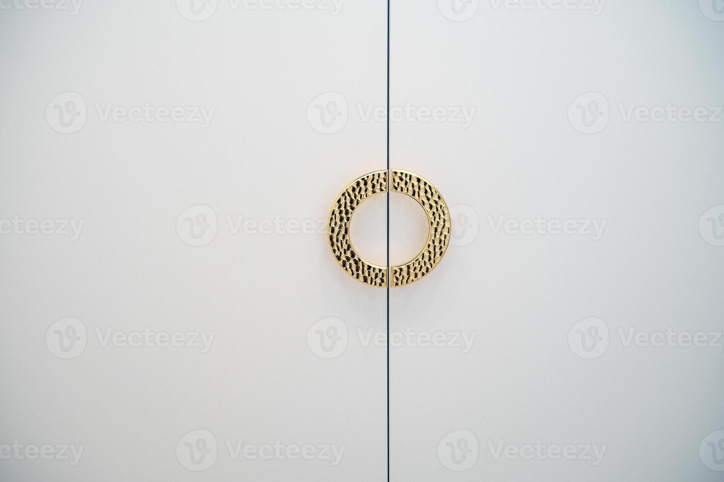 golden round handle on white cabinet doors. the handle has a rounded shape, ribbed structure. space for text photo