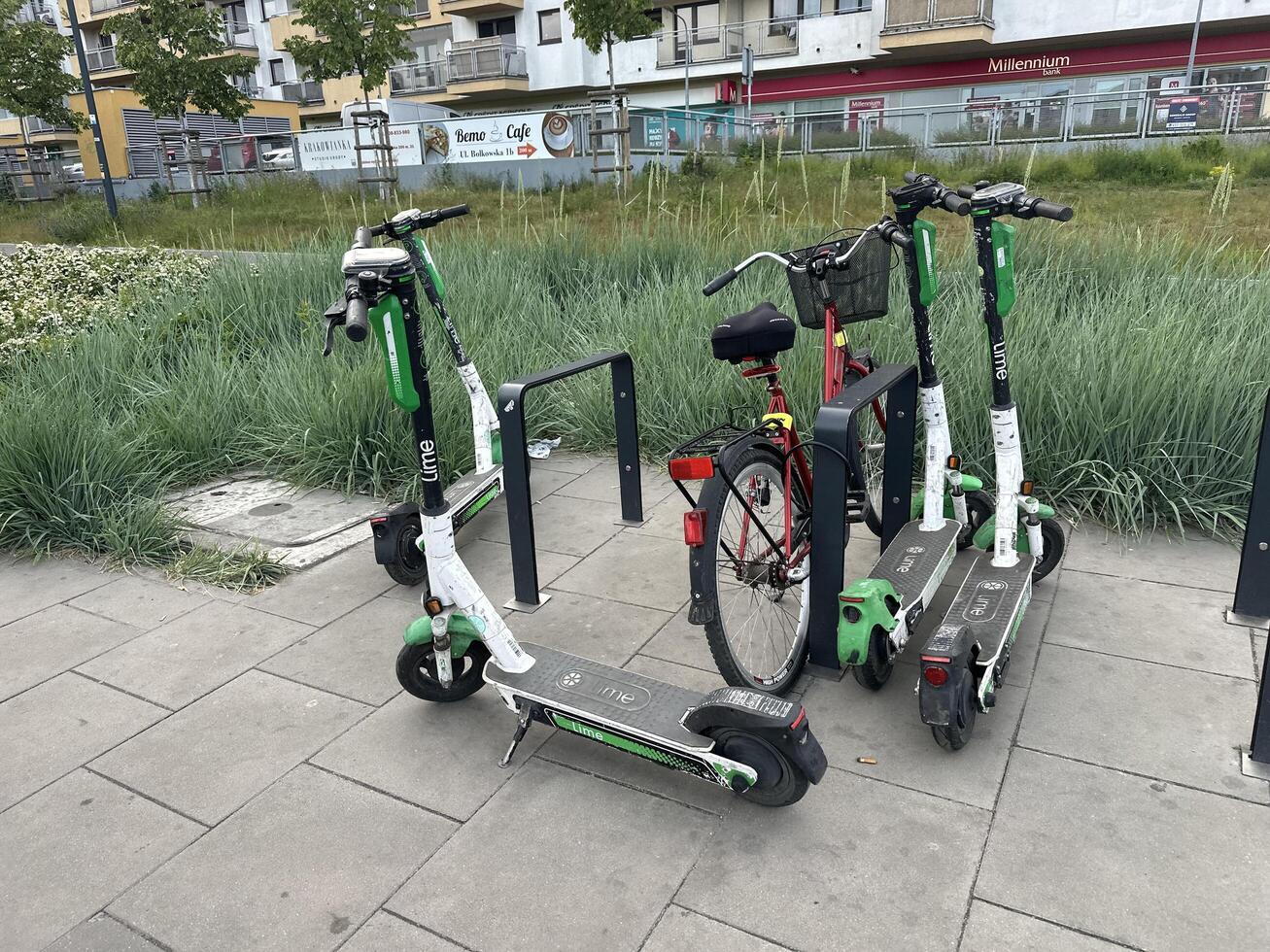Warsaw, Poland - May 22, 2025 Electric scooters and bicycle parked in urban area with green grass and modern buildings in the background, showcasing eco-friendly transportation options photo