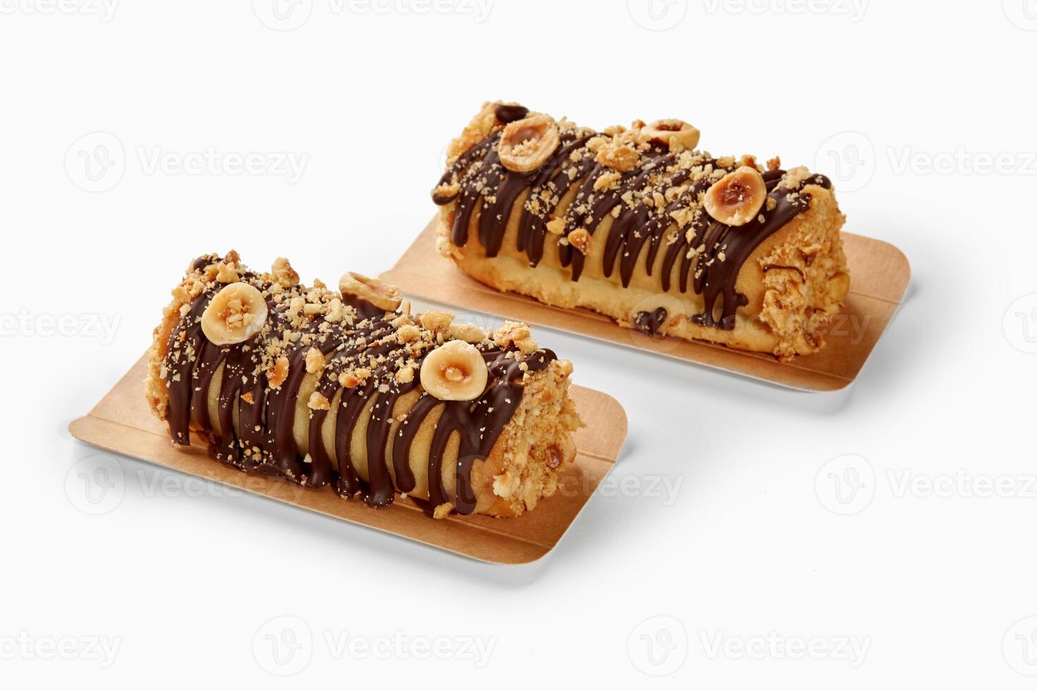 Two hazelnut and chocolate covered mini cakes resting on cardboard trays photo