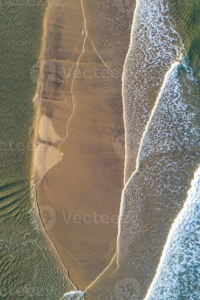 drone shot capturing the delicate foam lines where sea meets shore at sunset, aerial top down image by drone. Summer background concept photo