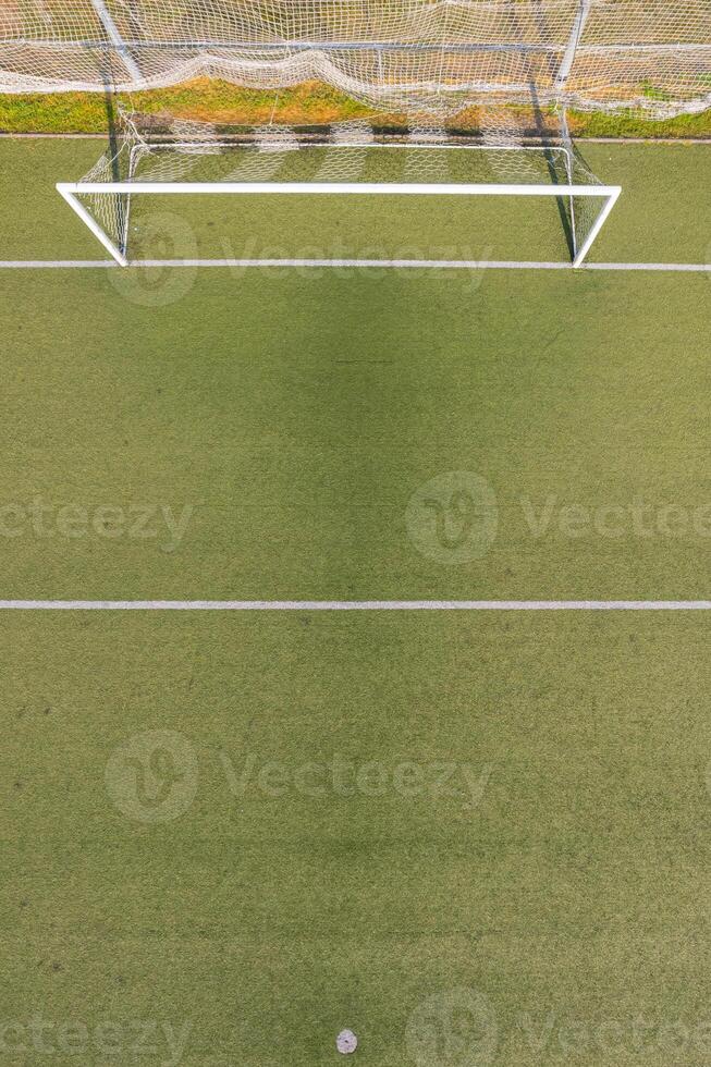 aerial view of an empty soccer goal on a green artificial turf field, aerial drone top down view photo