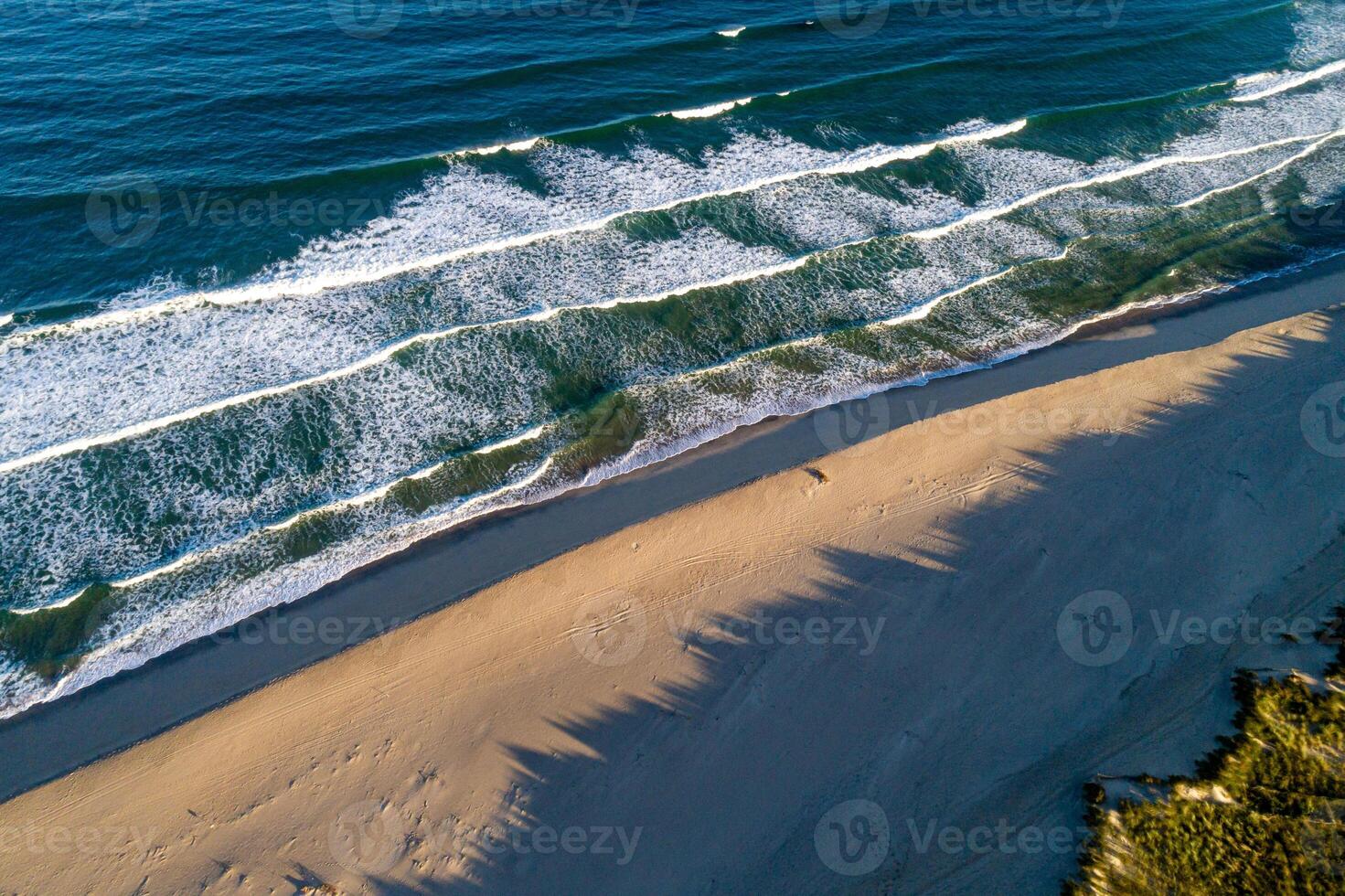 serene seascape a peaceful beach with foamy waves and long, dramatic shadows, aerial top down image by drone. Summer background concept photo