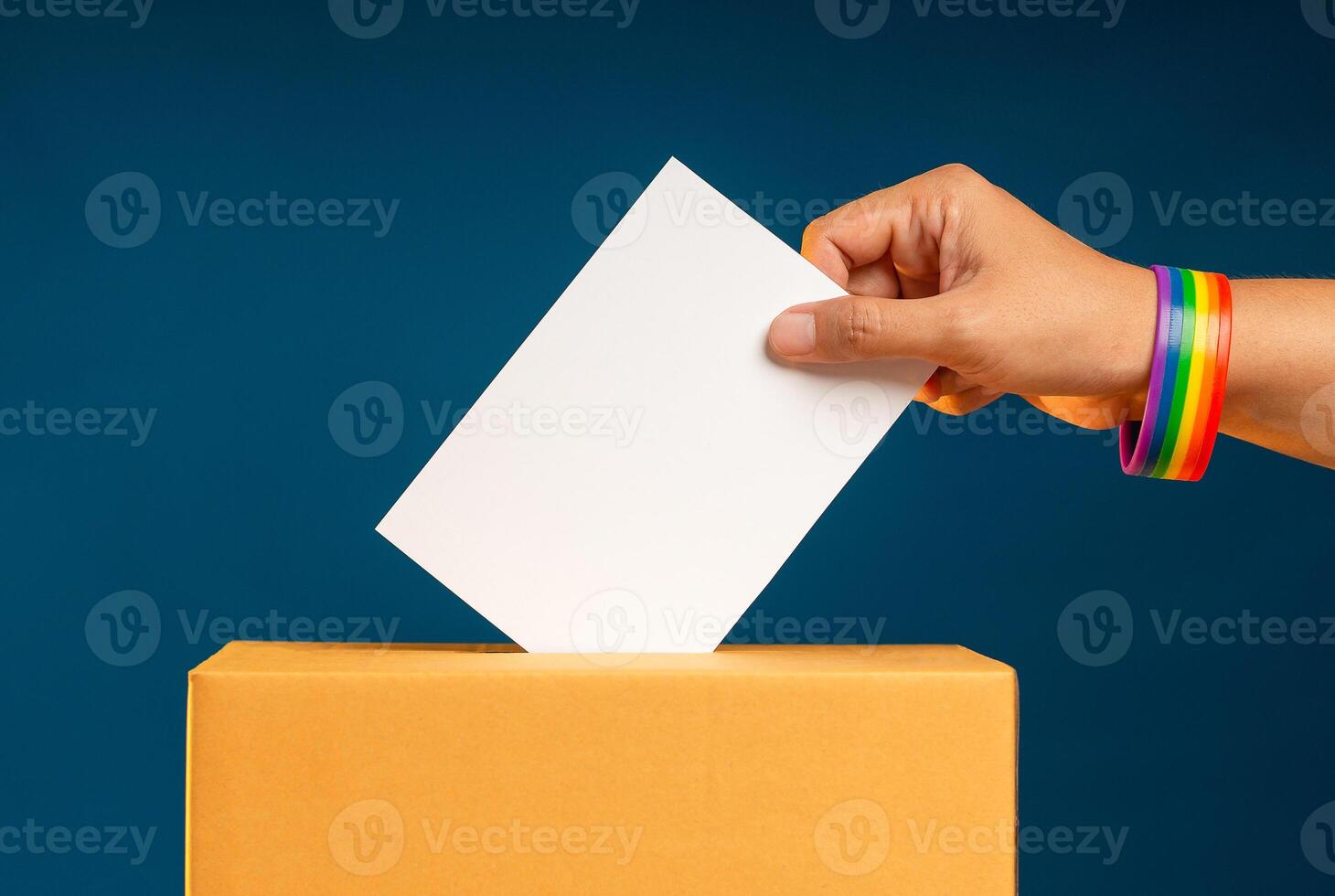 Election day. Hand voter holding ballot paper putting into the voting box at place election against a blue background photo