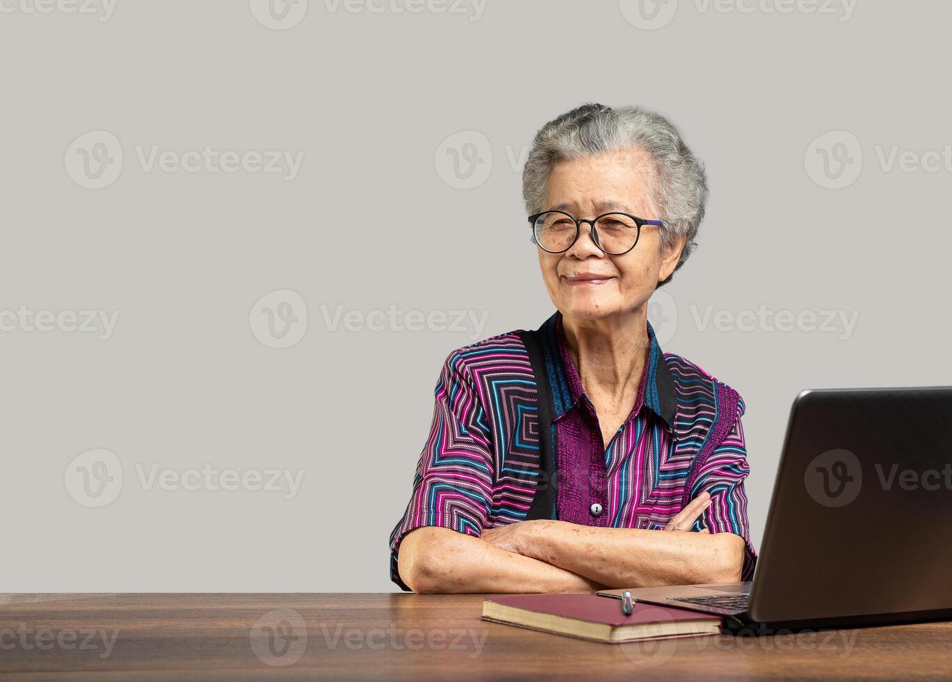 Portrait of an elderly Asian woman looking at the camera with a smile while sitting at the table photo