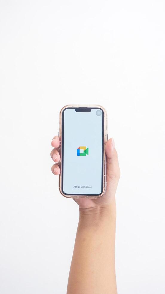 Yogyakarta, Indonesia, 2025 - Hand holdingHand holding smartphone that shows opening page of Google Meet application on screen isolated on white background photo