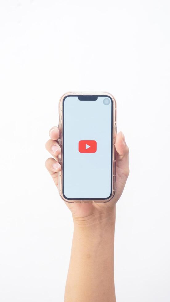 Yogyakarta, Indonesia, 2025 - Hand holding smartphone that shows front page of Youtube application platform on the screen isolated on white background photo