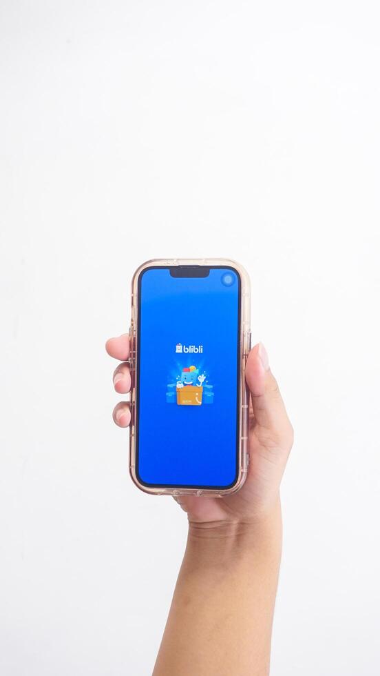 Yogyakarta, Indonesia, 2025 - Hand holding smartphone showing opening page of Blibli, e-commerce platform from Indonesia isolated on white background photo