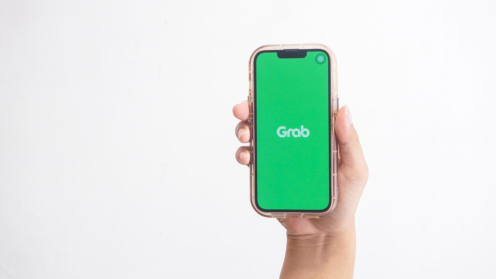 Yogyakarta, Indonesia, 2025 - Hand holdingHand holding smartphone that shows opening page of Grab application, on-demand service platform, on screen isolated on white background photo