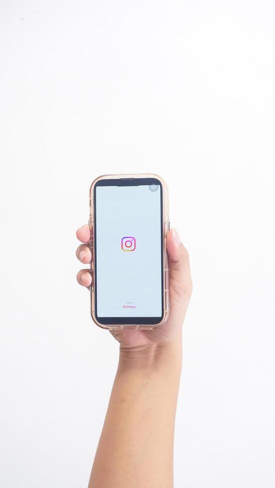 Yogyakarta, Indonesia, 2025 - Hand holdingHand holding smartphone that shows front page of Instagram platform application on screen isolated on white background photo