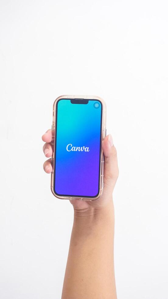 Yogyakarta, Indonesia, 2025 - Hand holding smartphone showing front page of Canva on screen isolated on white background photo