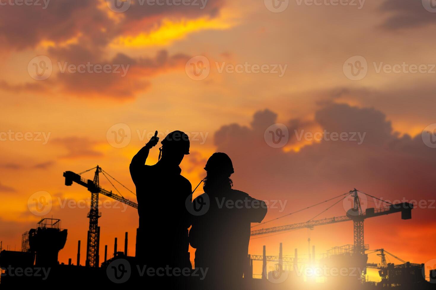 Silhouette of Engineer and worker checking project at building site background, Worker showing thumbs up construction site at sunset in evening time photo