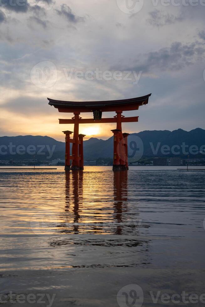 The Famous red torii gate of Itsukushima shrine at sunset in Miyajima, Japan photo