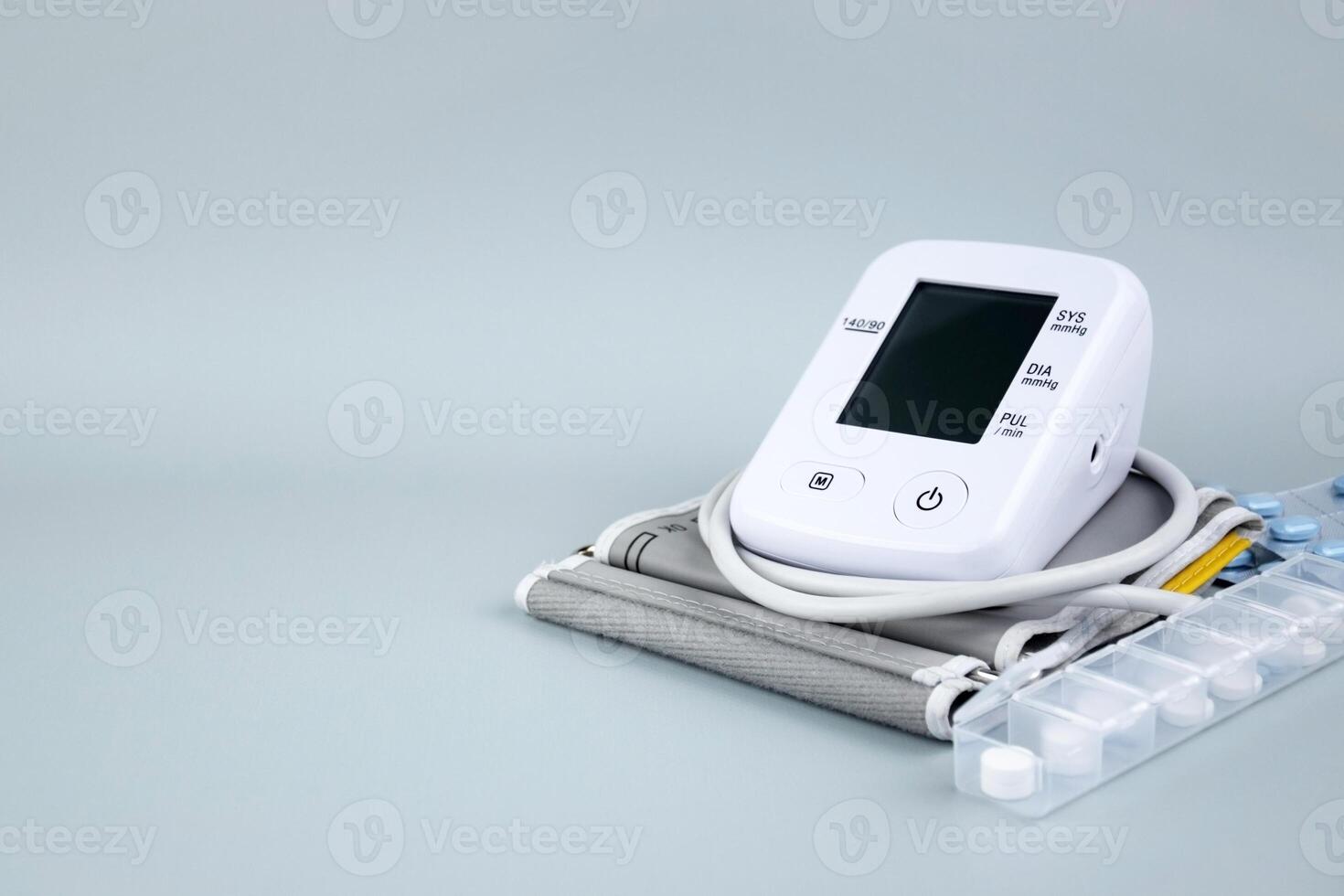 Digital blood pressure tonometer and pack of pills on the blue background with copy space. photo