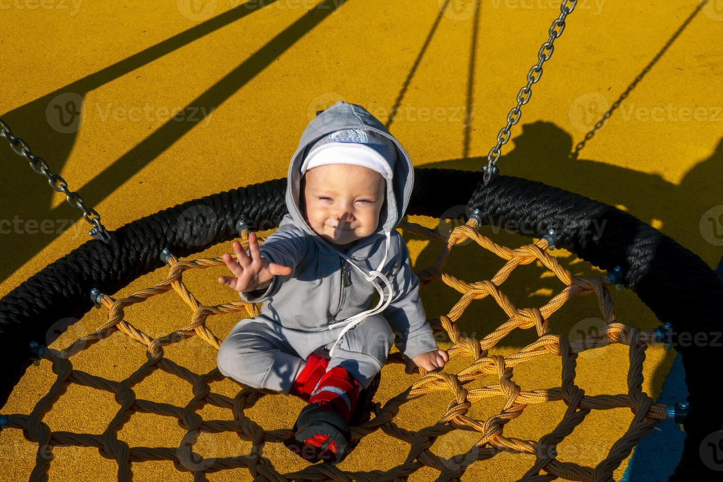 Little baby on spider web nest swing. Baby girl boy 1 year swinging on a swing in the yard photo
