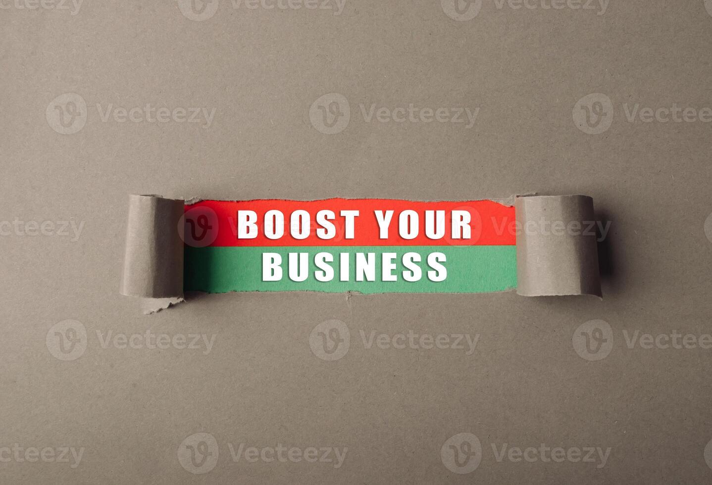 Torn piece of paper with the words boost your business written on it photo