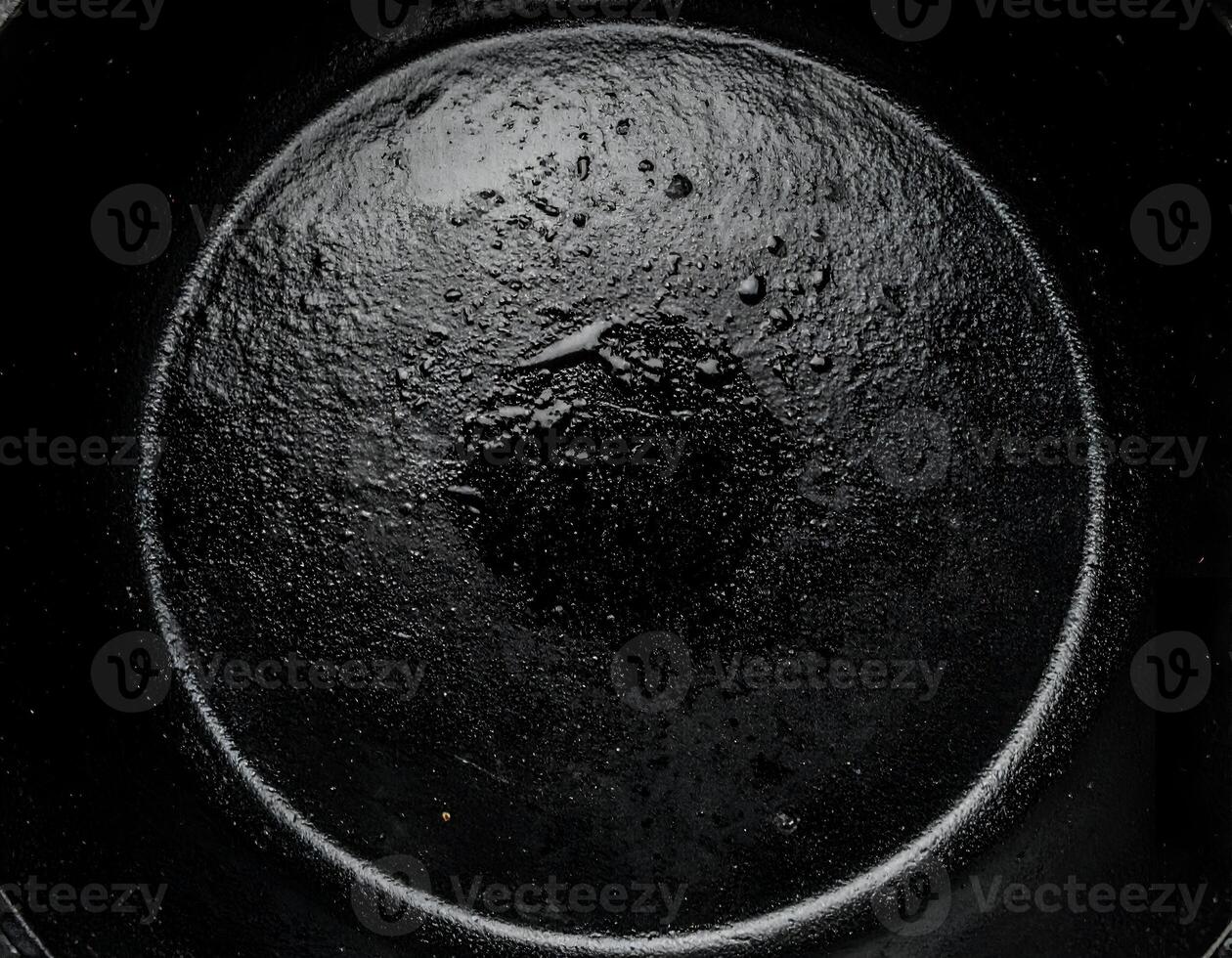 minimalist top view of cast iron skillet surface with subtle oily center and moody black texture background for cooking or kitchen design photo