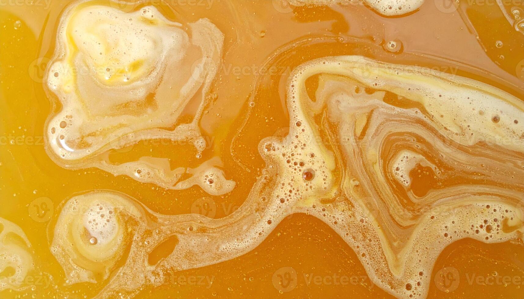 abstract close-up of melted golden wax pool texture with natural swirls and foamy surface, top view fluid wax movement for background design photo