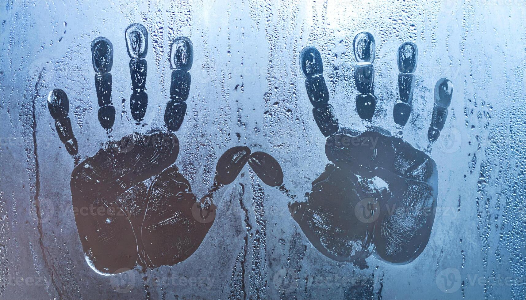 human handprints on wet foggy glass window with condensation and water droplets, symbol of touch, mystery, isolation, or human presence photo