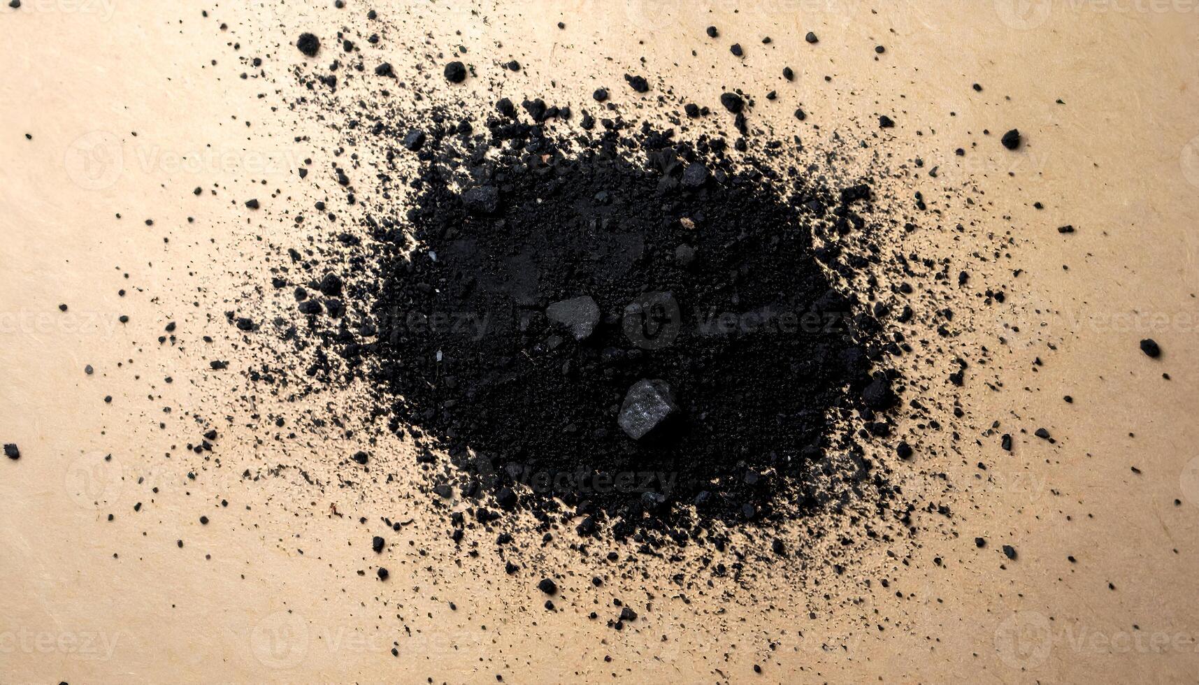 charcoal dust scattered on brown paper texture, top view of natural black powder with rough fragments for artistic, cosmetic or organic design concepts photo