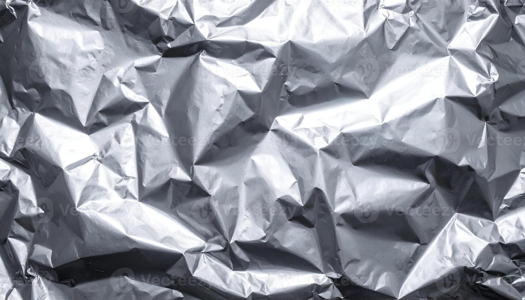 crinkled silver thermal foil texture background with shiny reflective surface, abstract metallic material for packaging and design photo