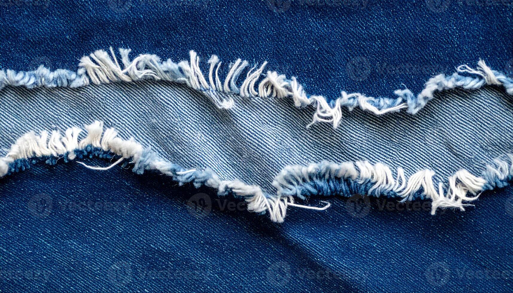 torn denim fabric with frayed edges, macro close-up of ripped blue jeans showing inner thread texture for textile or fashion background photo